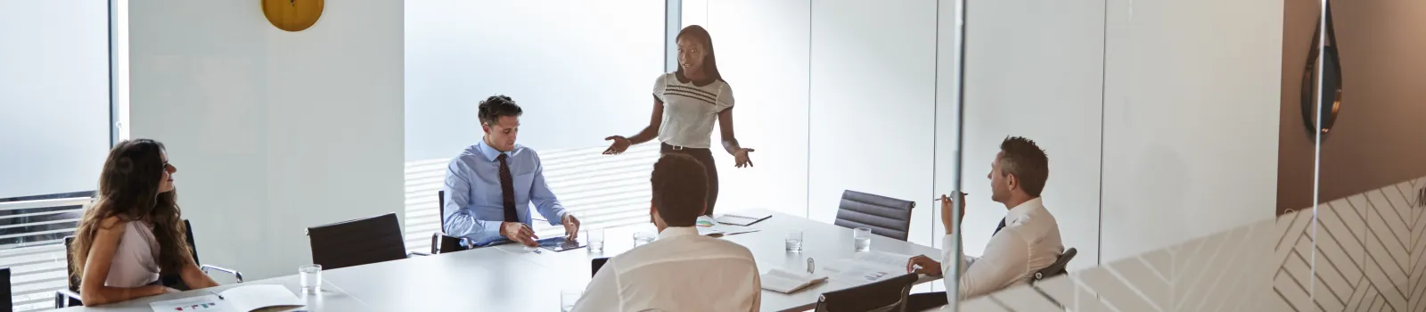 masthead businesswoman giving boardroom presentation viewed through meeting room window