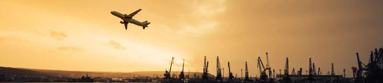 masthead airplane flying over commercial container port