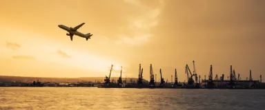 masthead airplane flying over commercial container port